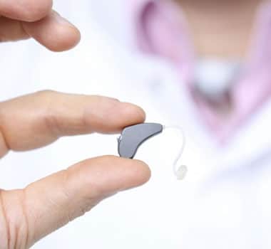 person holding hearing aid devices