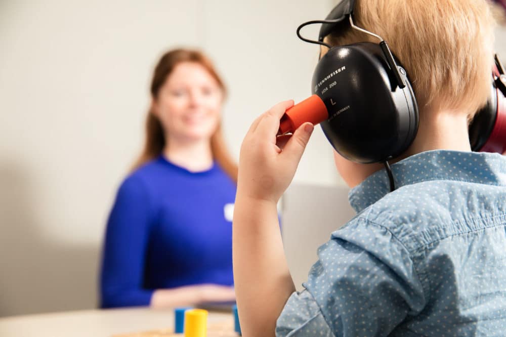 Audiologist with child in headphones for test