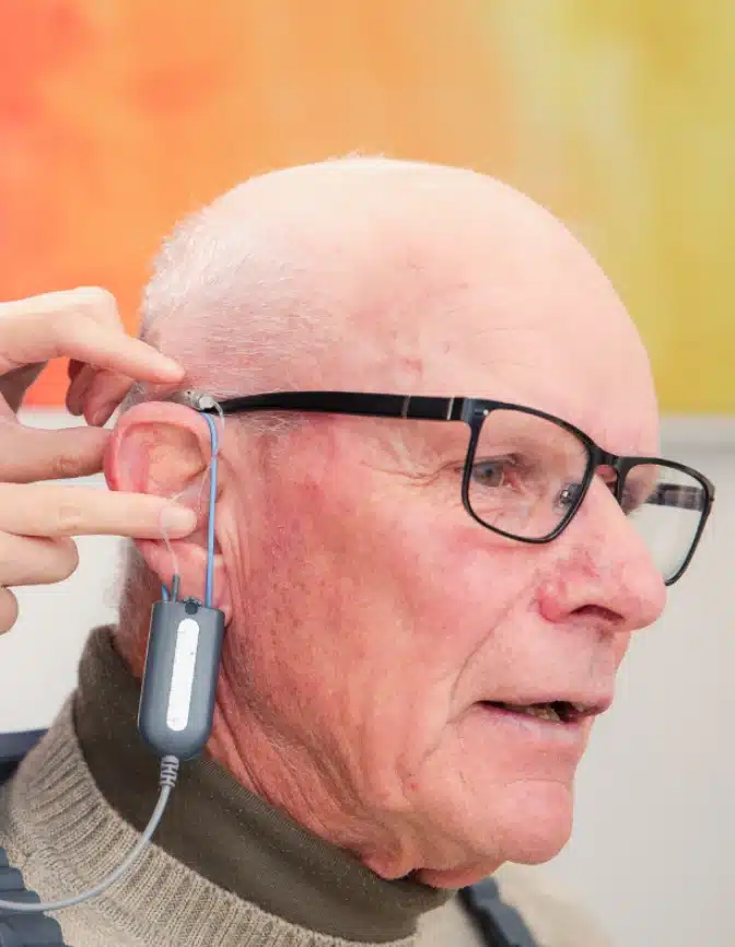 Elderly man getting hearing aid fitted