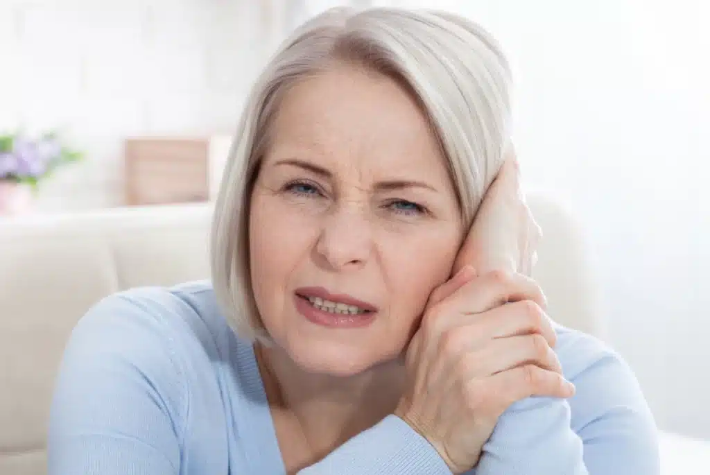 Woman holding ear has Tinnitus